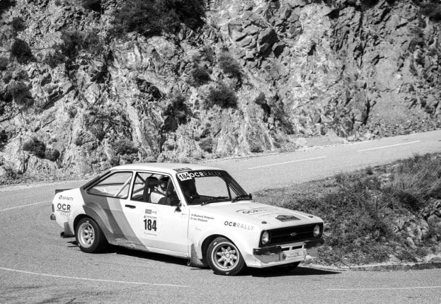 Rally car driving down hill, black and white